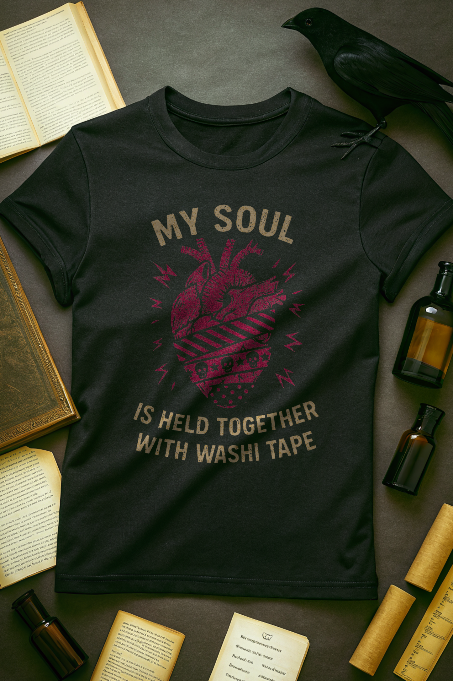 flat lay of black tee with anatomical heart graphic and text, my soul is held together with washi tape.