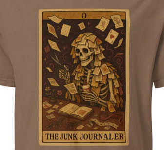 Brown t-shirt with a tarot card design of a skeleton covered in paper scraps and text 'The Junk Journaler' on a tan background.