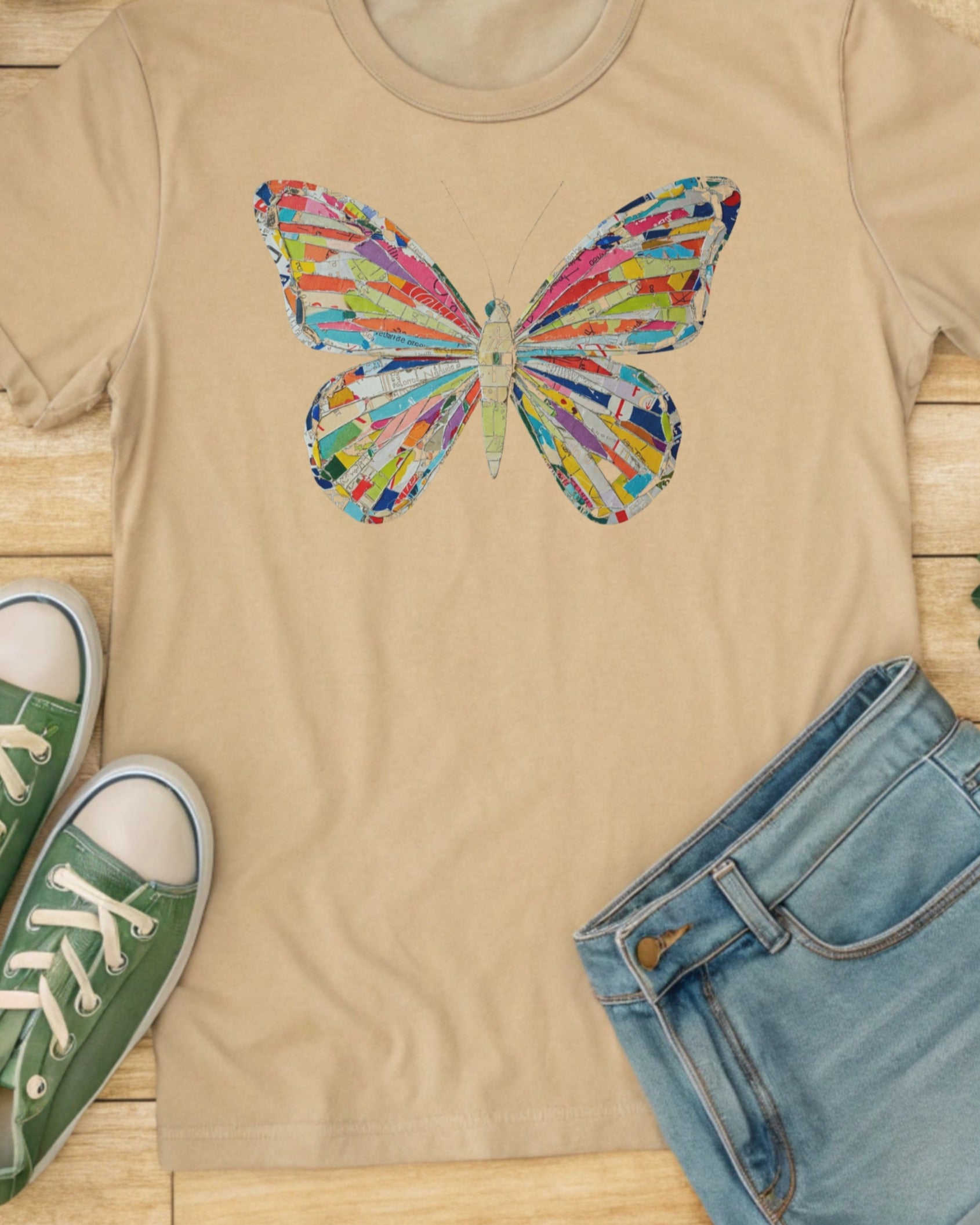 A colorful, collaged butterfly graphic on a tan t-shirt.