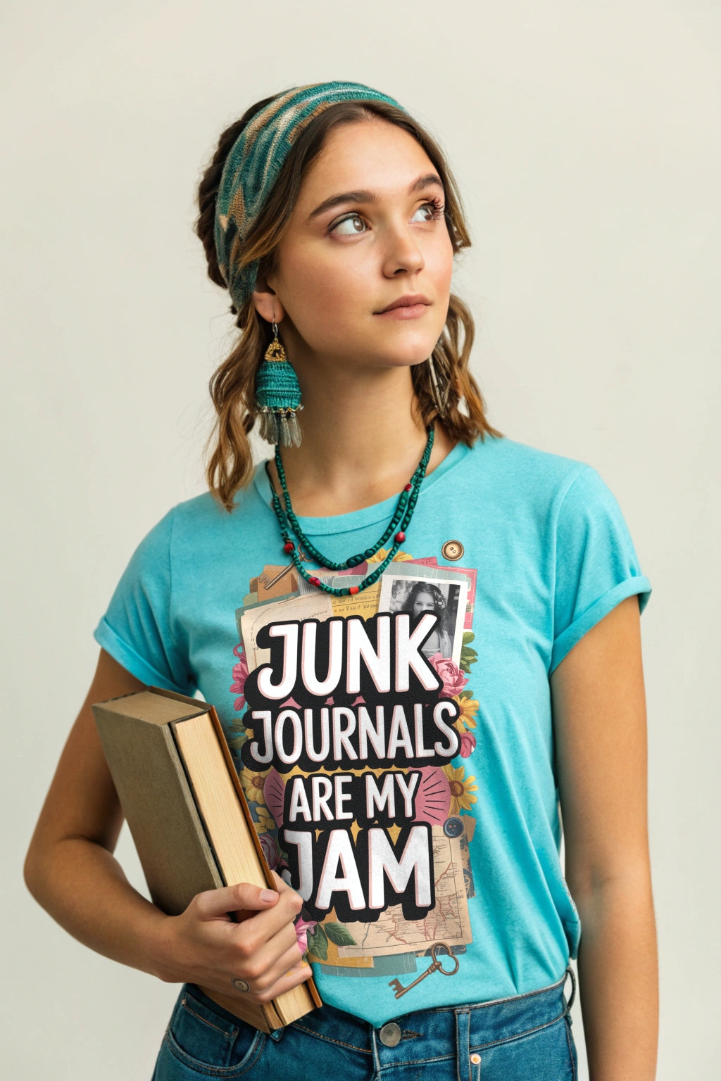 Woman wearing a t-shirt with 'Junk Journals Are My Jam' text, holding a book. T-shirt is Lagoon Blue.