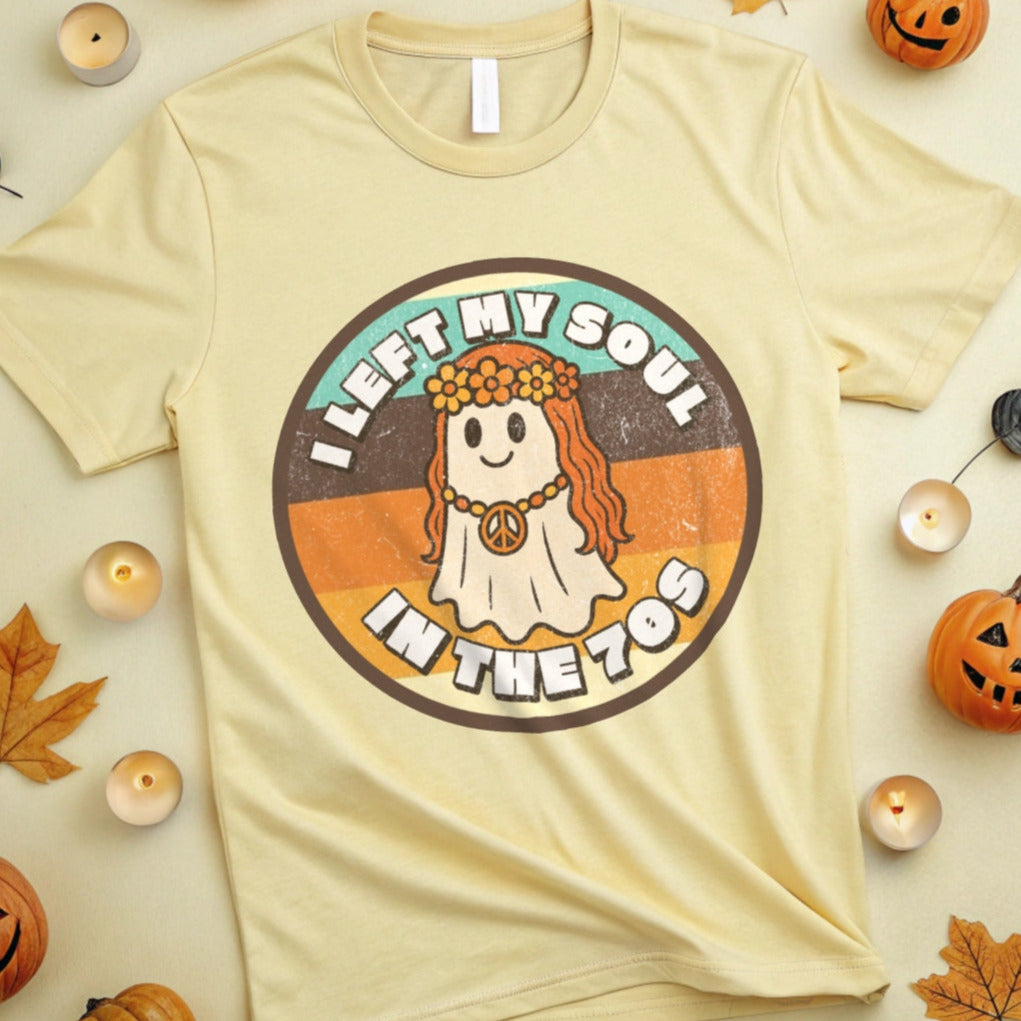 Tan t-shirt with a graphic design featuring a 70s flower child ghost and the text, "I left my soul in the 70s" surrounded by Halloween decorations on a beige background.