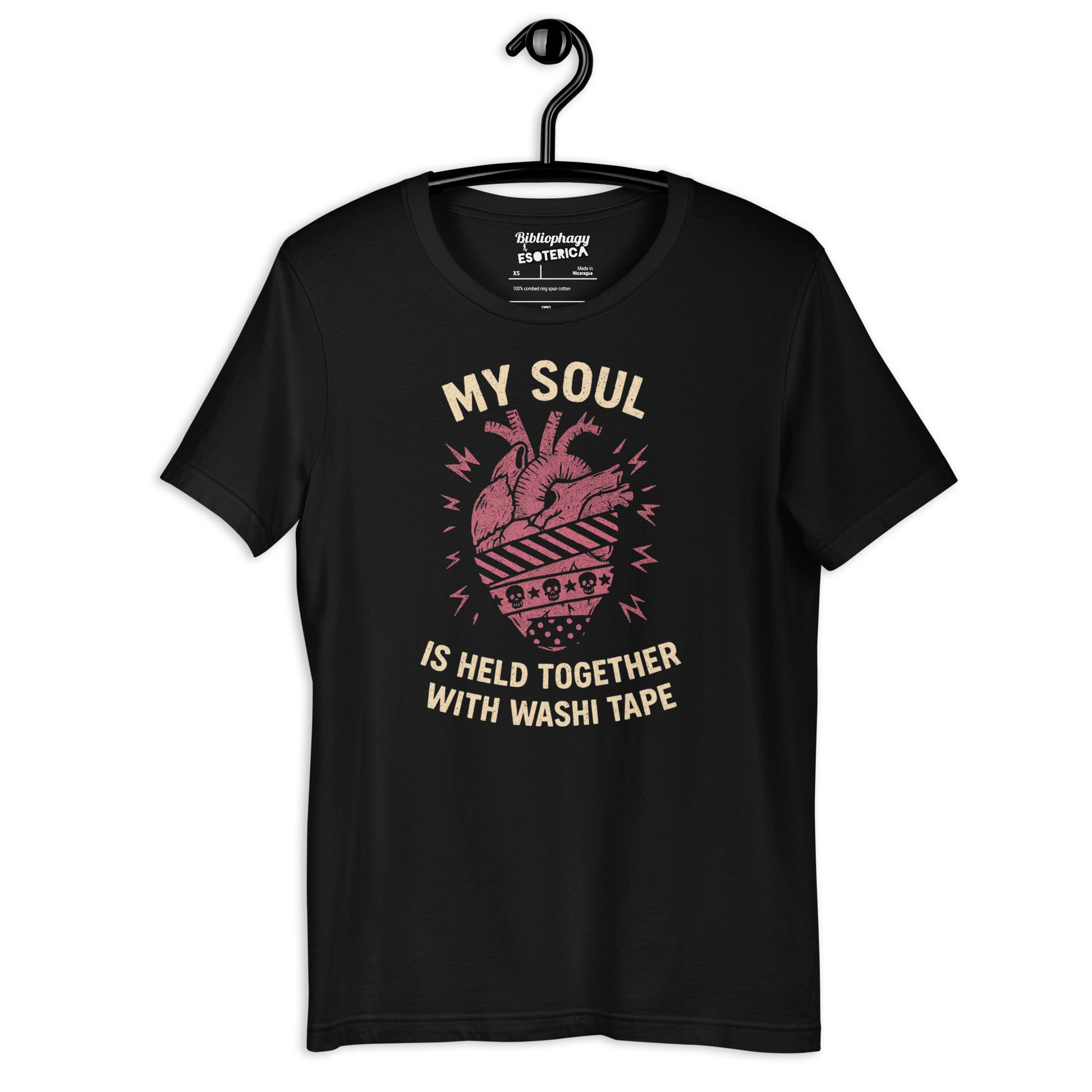 Tee hanging on a hanger. Tee has a red anatomical heart with three different patterns of washi tape wrapping around it. Text says "my soul is held together with washi tape."